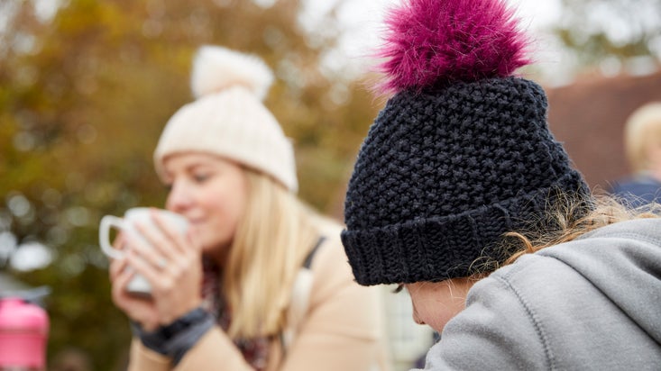 Two visitors sipping hot drinks outside a cafe